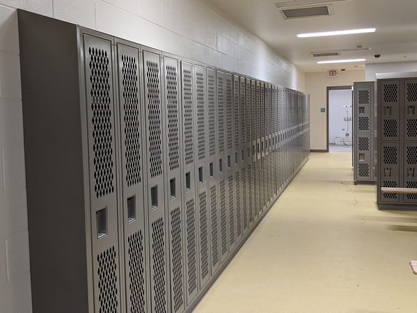 Single-tier Heavy Duty Ventilated Athletic Lockers in a locker room, with a dark gray finish.