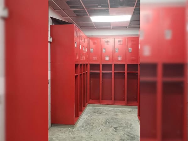 Open front Heavy Duty Ventilated Athletic Lockers with additional storage above in a fire station, with a red finish.