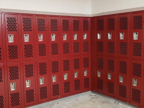 Two-tier Heavy Duty Ventilated Athletic Lockers in a locker room with a red finish, by Republic Storage Products.