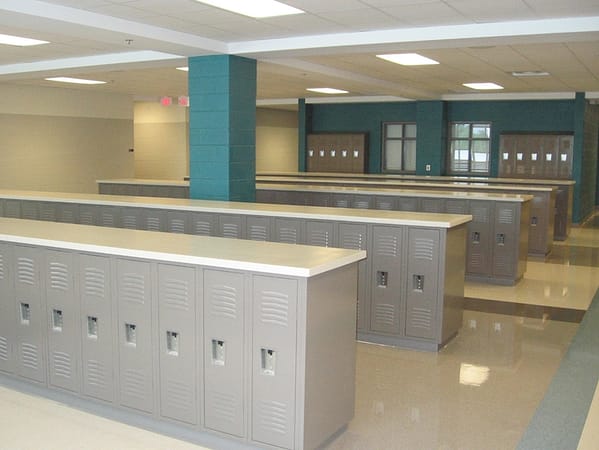 Single-tier half-height metal lockers in a hallway, with a tan finish.