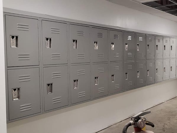 Two-tier standard metal lockers with a custom design in a hallway, with a gray finish.