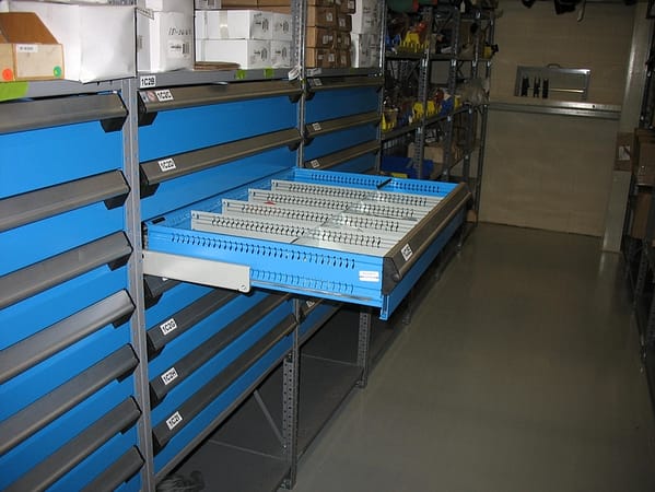 Blue metal drawers on gray metal shelving along with other products.
