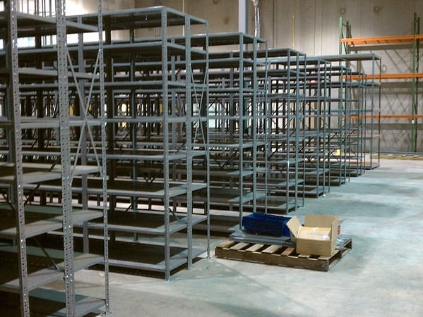 Gray metal shelving with pallet rack in the background.