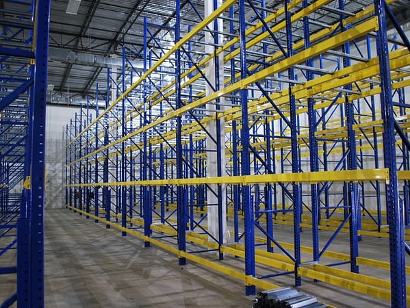Pallet rack with blue uprights and yellow beams in a warehouse.