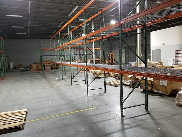 Pallet rack with wire deck in a warehouse with product behind ready to be loaded.