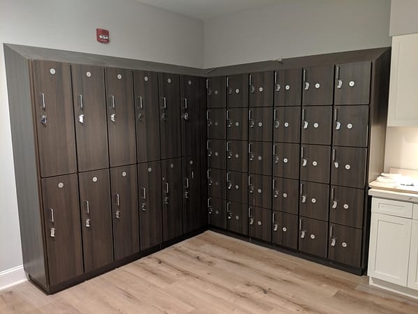 Two-tier and five-tier phenolic lockers in a room, with a wood style finish.