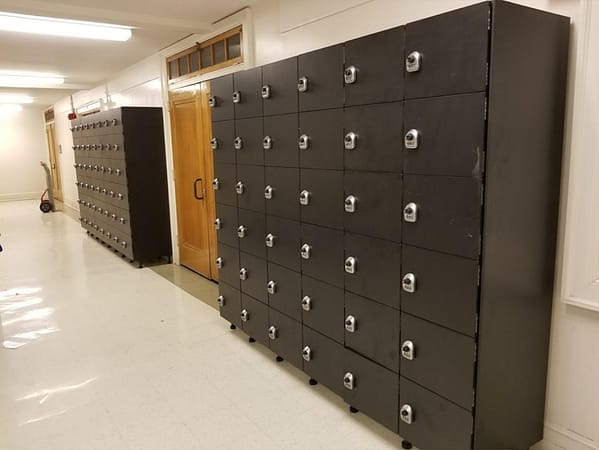 Six-tier phenolic lockers in a hallway, with a black finish.