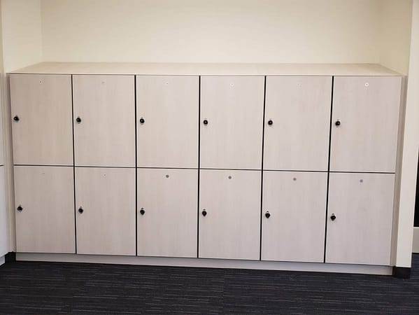 Two-tier plastic laminate lockers in a hallway, with a light gray finish.