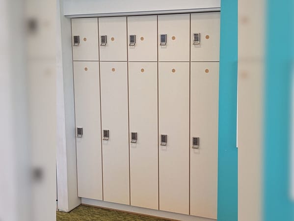 Two-tier plastic laminate lockers in a hallway, with a white finish.
