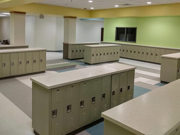 Single-tier half-height metal lockers in a hallway, with a tan finish.