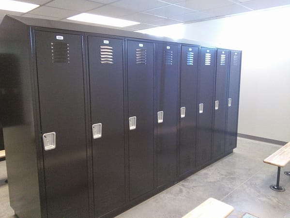 Single-tier metal lockers in a locker room, with a black finish.