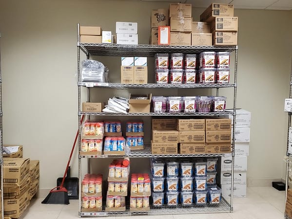Wire shelving filled with break room items in a storage room.