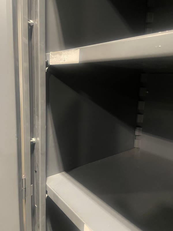 Close up showing the shelves are adjustable on the gray used two door storage cabinet